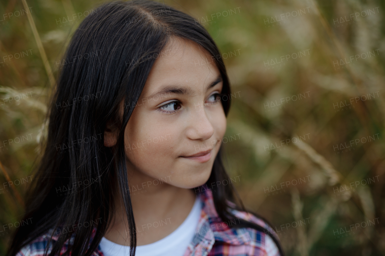 Portrait of beautiful young girl standing in nature, in the middle of tall grass with closed eyes, headshot. Copy space.