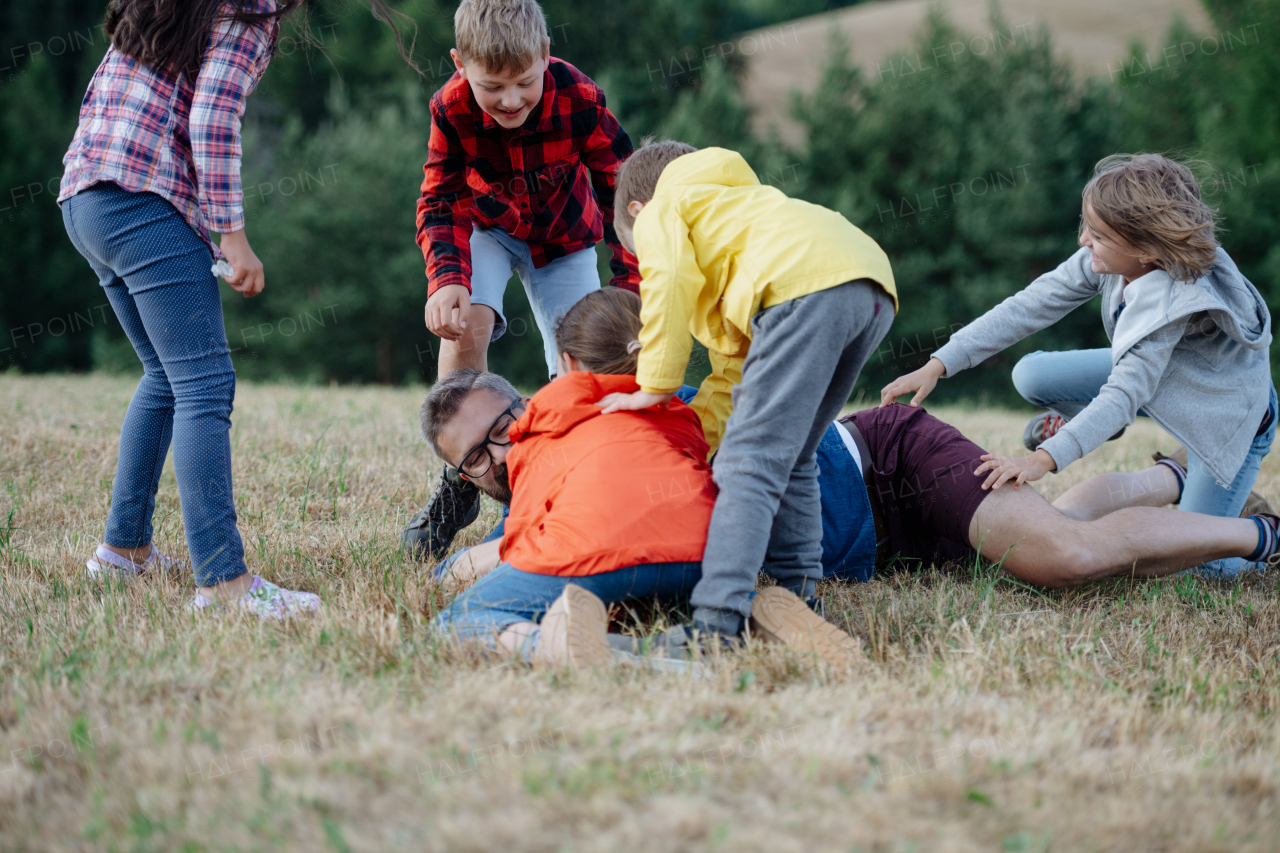 Young students playing with teacher outdoors, in nature, during field teaching class, running with ball, Dedicated teachers during outdoor active education.Teachers' Day.