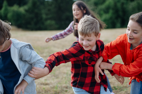 Young students playing with teacher outdoors, in nature, during field teaching class, having fun. Dedicated teachers during outdoor active education.Teachers' Day.