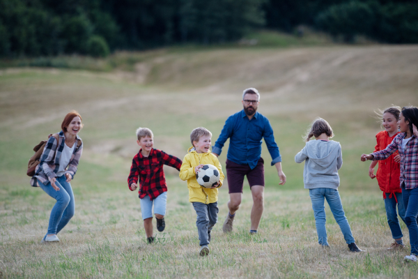 Young students playing with teacher outdoors, in nature, during field teaching class, running with ball, Dedicated teachers during outdoor active education.Teachers' Day.