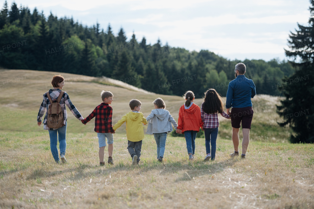 Young students walking across meadow during biology field teaching class, holding hands. Dedicated teachers during outdoor active education teaching about ecosystem and nature.