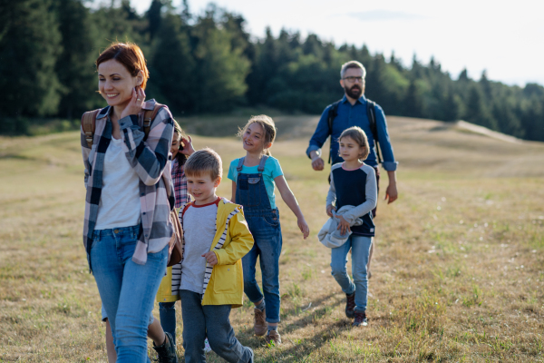 Young students walking across meadow during biology field teaching class. Dedicated teachers during outdoor active education teaching about ecosystem and nature.