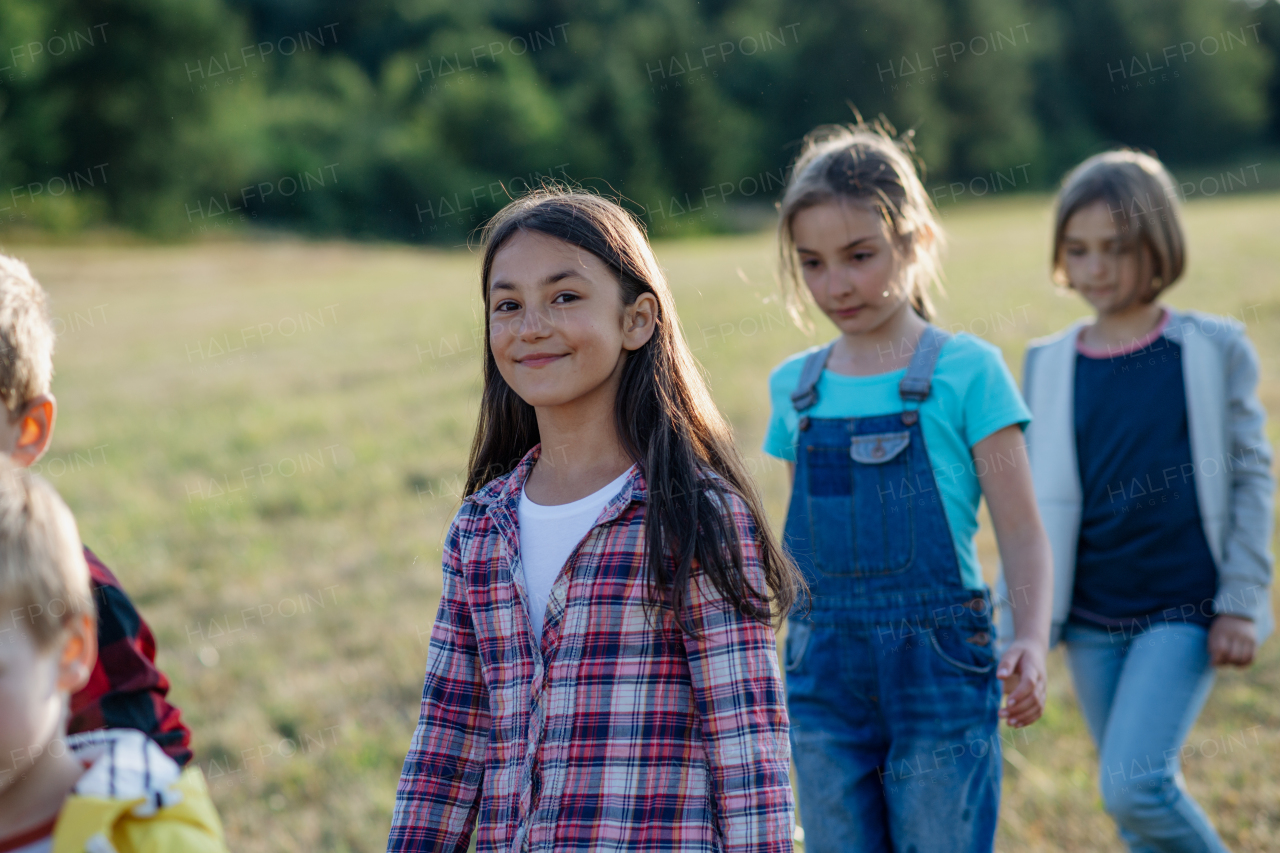 Young students walking across meadow during biology field teaching class. Dedicated teachers during outdoor active education teaching about ecosystem and nature.