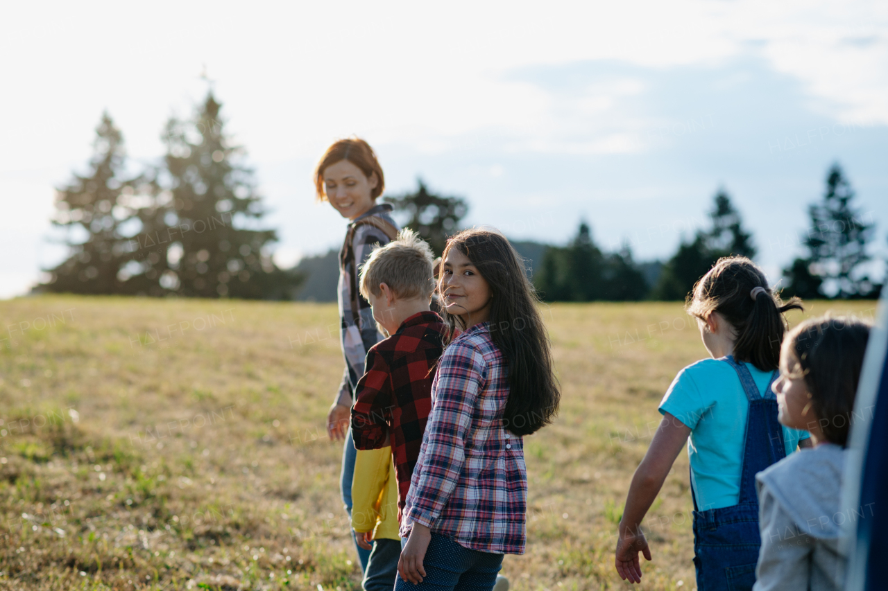 Young students walking across meadow during biology field teaching class. Dedicated teachers during outdoor active education teaching about ecosystem and nature.