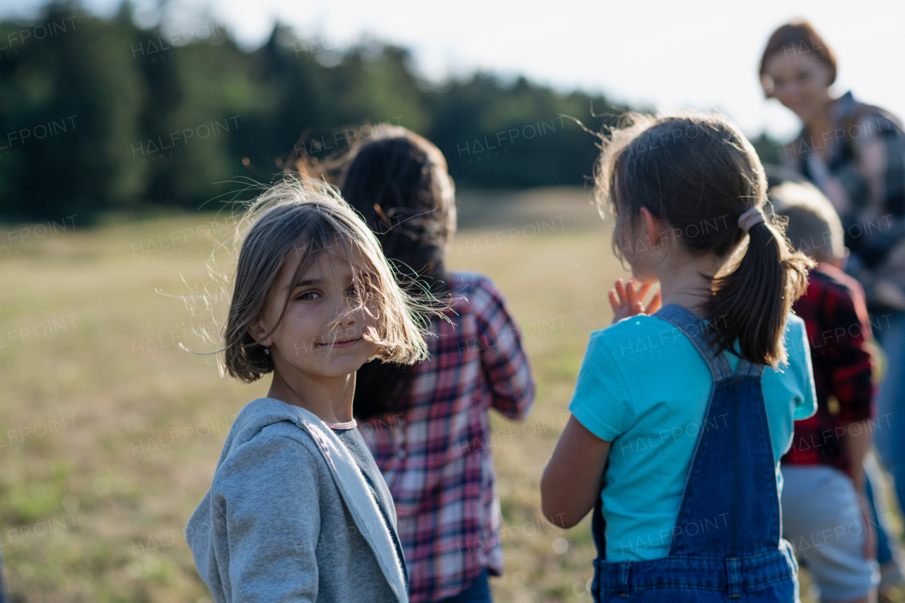 Young students walking across meadow during biology field teaching class. Dedicated teachers during outdoor active education teaching about ecosystem and nature.