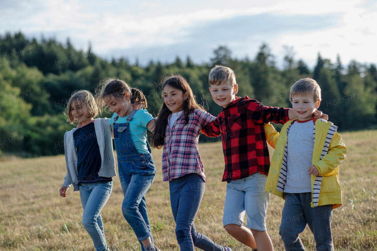 Portrait of young classmates, students during biology field teaching class, walking across meadow. Learning about ecosystem, ecology and nature.