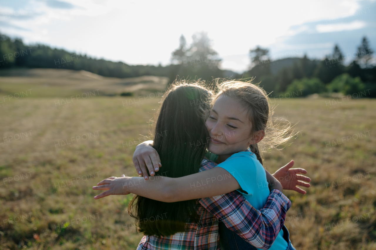 Cheerful young girl best friends spending time in nature, during sunset. Girls on walk, embracing.