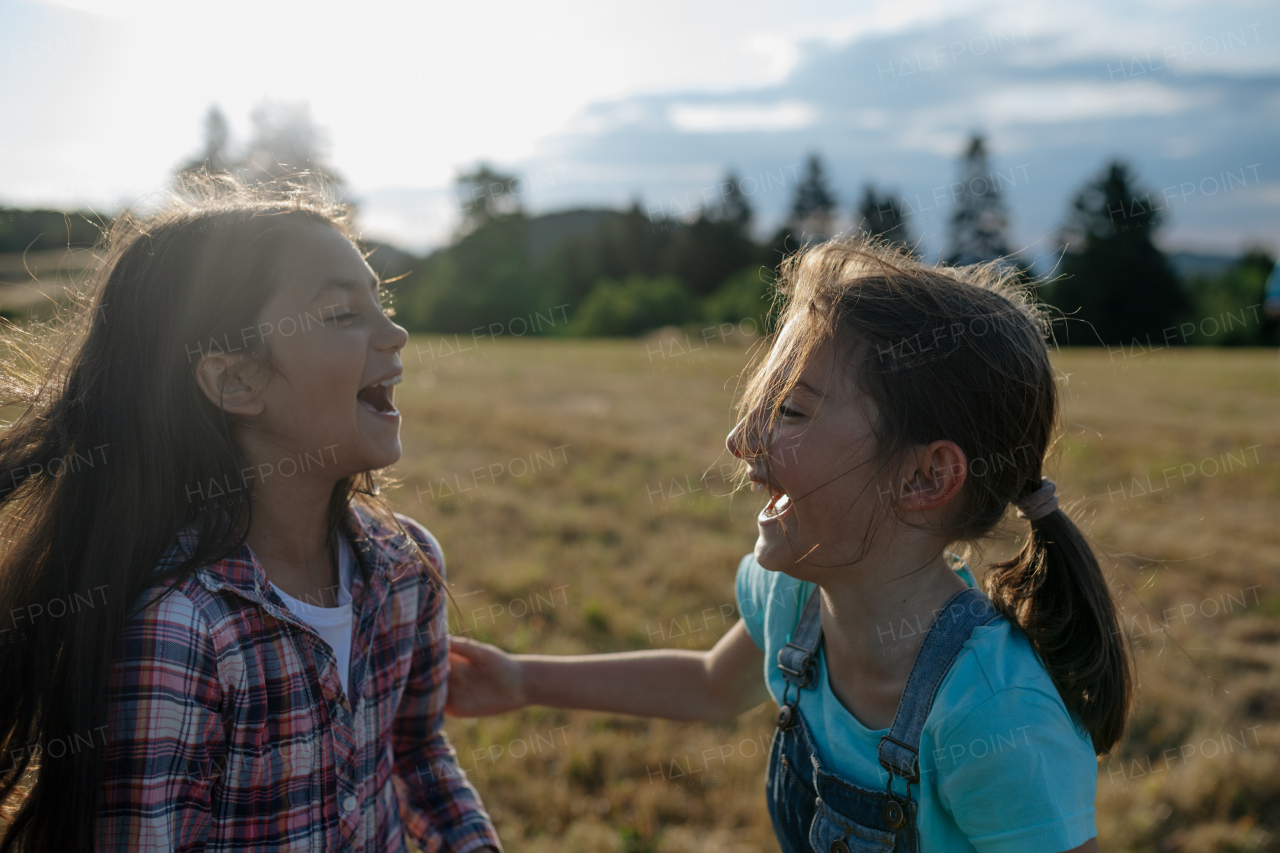 Cheerful young girl best friends spending time in nature, during sunset. Girls on walk, embracing.