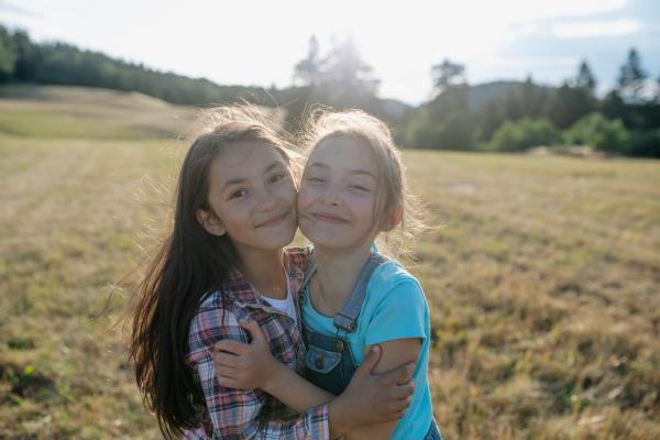 Cheerful young girl best friends spending time in nature, during sunset. Girls on walk, embracing.