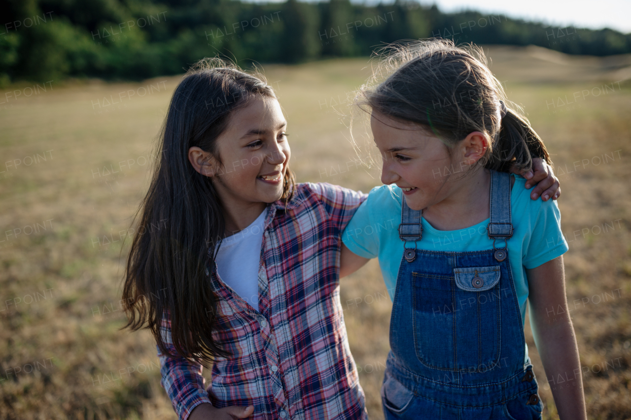 Cheerful young girl best friends spending time in nature, during sunset. Girls on walk, embracing.