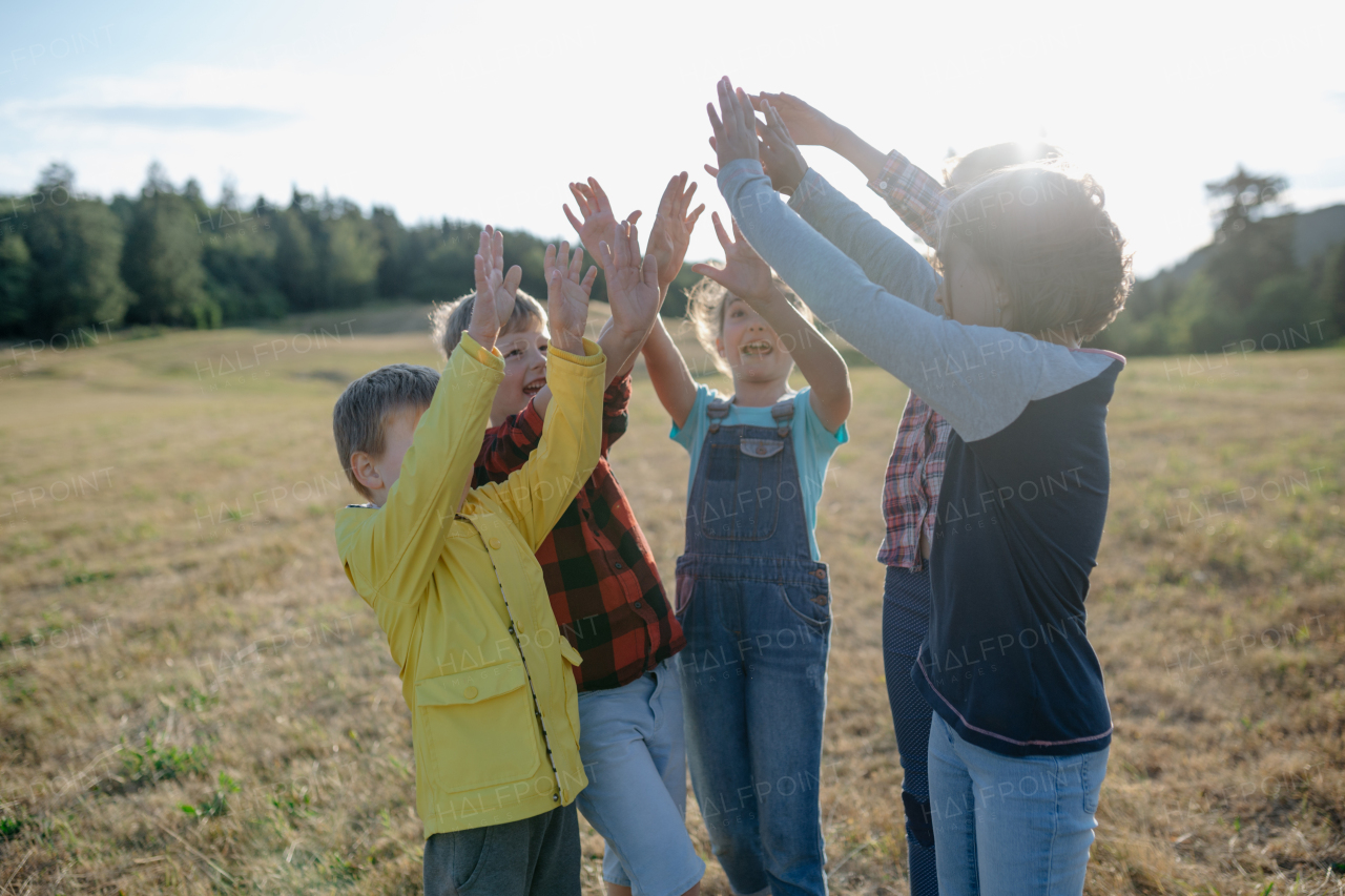 Portrait of young classmates, students during biology field teaching class, successful experiment, hands in air. Learning about ecosystem, ecology and nature. Teamwork