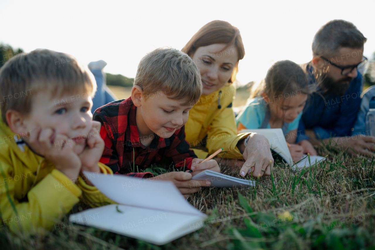 Young students learning about nature, forest ecosystem during biology field teaching class, writing notes. Teachers talking with children during outdoor active education. Teachers day.