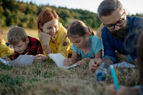 Young students learning about nature, forest ecosystem during biology field teaching class, writing notes. Teachers talking with children during outdoor active education. Teachers day.