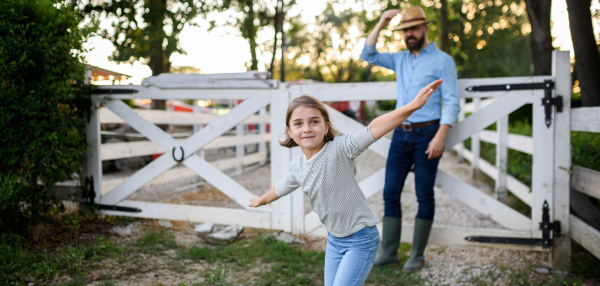 Portrait of a farmer family, father and young daughter standin on wooden fence on family farm. Concept of multigenerational farming.