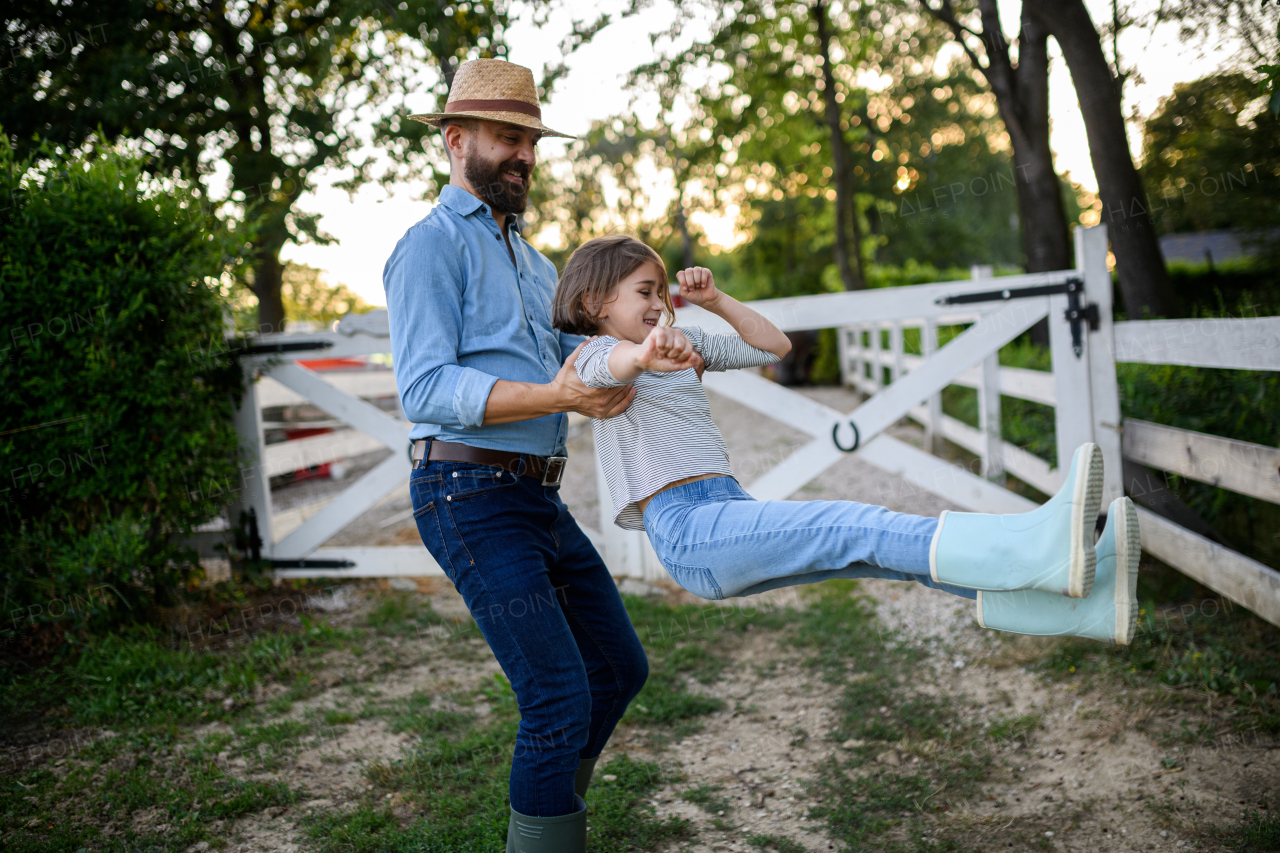 Father and young daughter having fun on a family farm, farmer family. Concept of multigenerational farming.