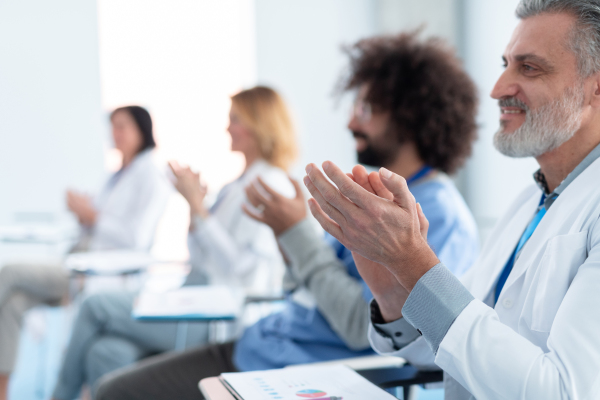 Group of doctors on conference, medical team sitting and clapping after speech. Medical experts attending an education event, seminar in board room.