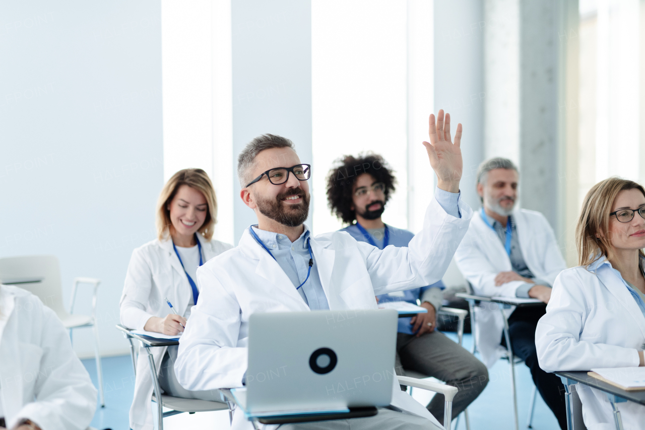 Medical team on conference, doctor raising hand asking question to speaker. Medical experts attending an education event, seminar in board room