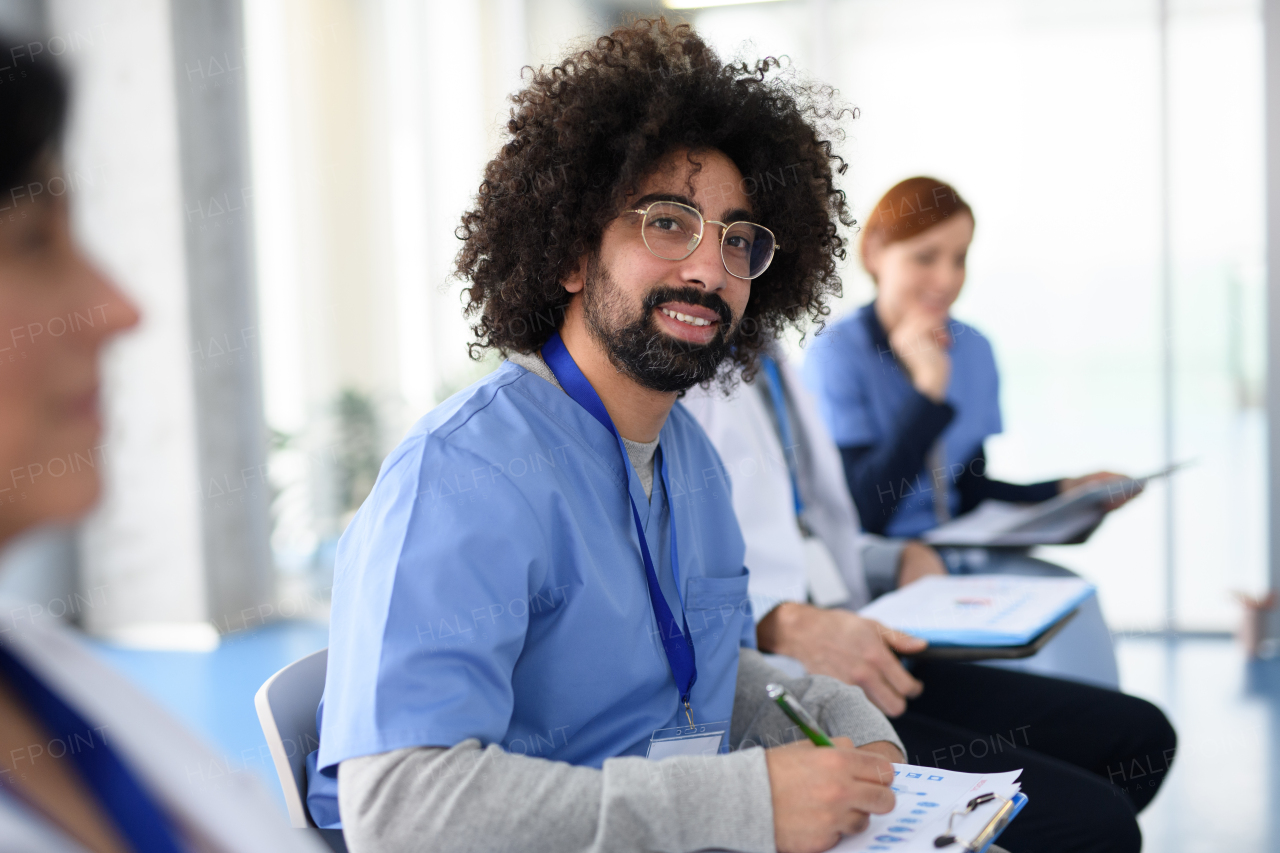 Portrait of doctor during conference, medical team sitting and listening to speaker, presenter. Medical experts attending an education event, seminar in board room.