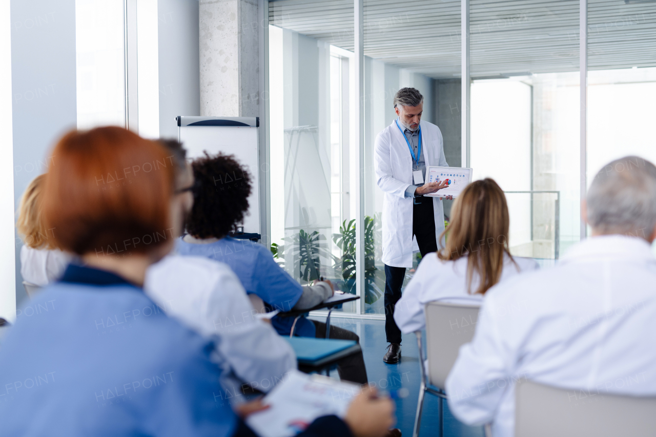 Doctor as speaker at conference for group of healtcare workers, medical team sitting and listening presenter. Medical experts attending an education event, seminar in board room.