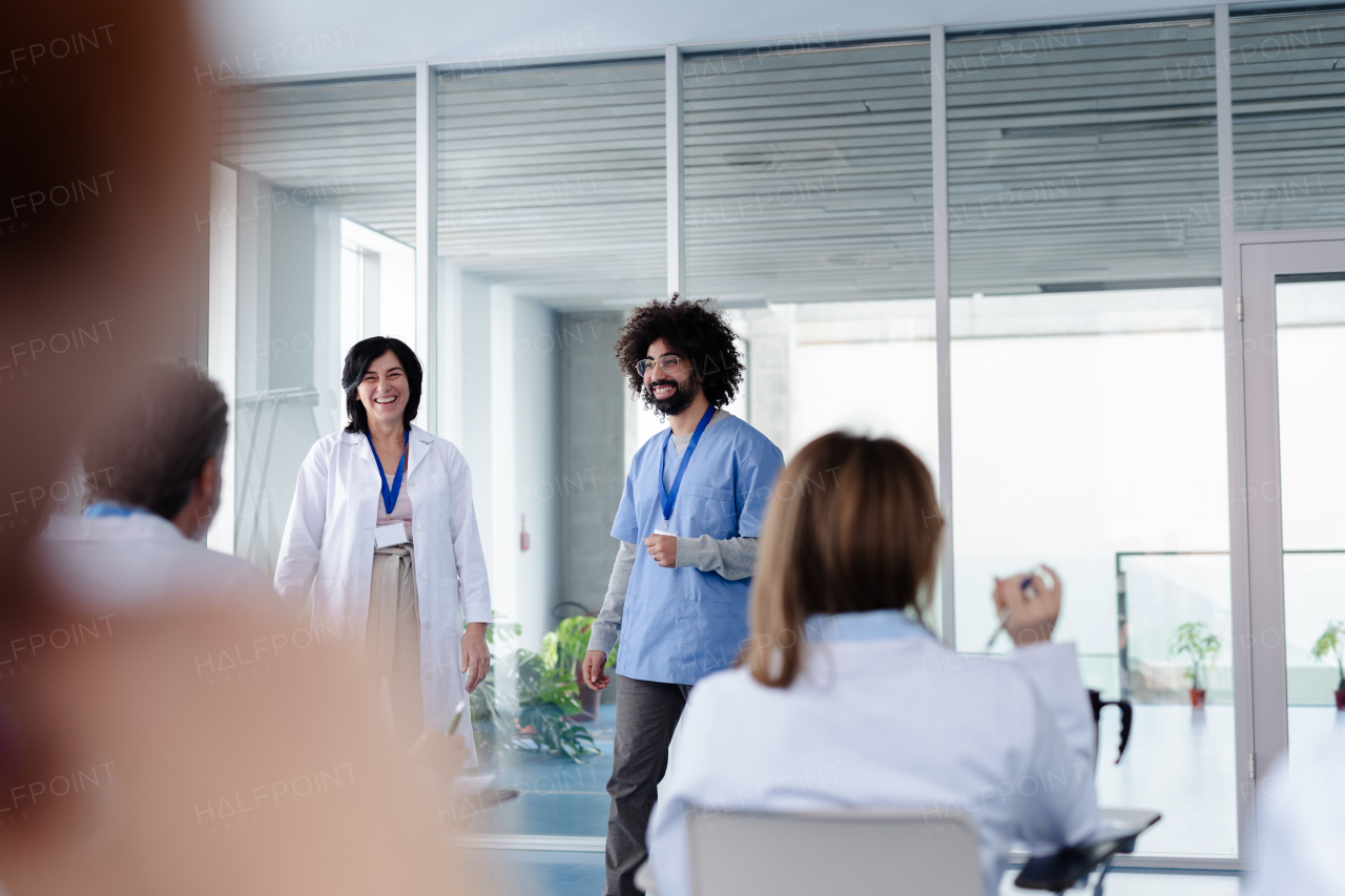 Female doctor as speaker at conference for group of healtcare workers, medical team sitting and listening presenter. Medical experts attending an education event, seminar in board room.