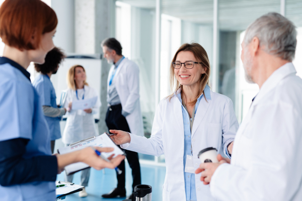 Group of doctors talking during conference, sharing best practices, discussing research findings. Medical networking. Medical experts attending an education event, seminar in board room.