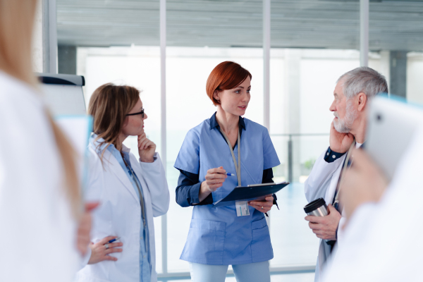 Group of doctors talking during conference, sharing best practices, discussing research findings. Medical networking. Medical experts attending an education event, seminar in board room.