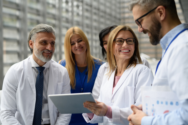 Group of doctors discussing test results, looking on tablet, medical team discussing patients diagnosis, searchign for right treatments.