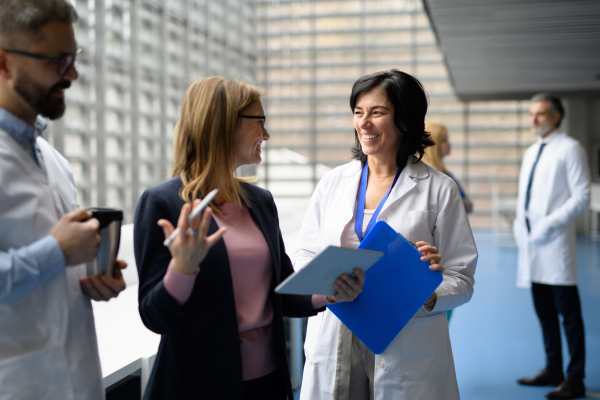 Doctors talking to pharmaceutical sales representative, presenting new pharmaceutical product. Hospital director, manager talking with doctors team.