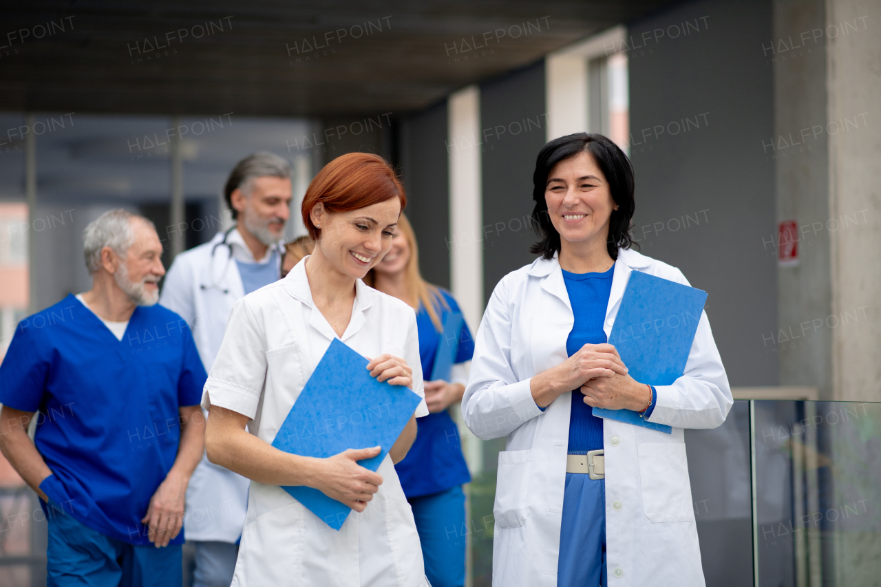 Team of doctors discussing unique medical case, walking across corridor. Colleagues, doctors team discussing patients diagnosis. in modern hospital, clinic.