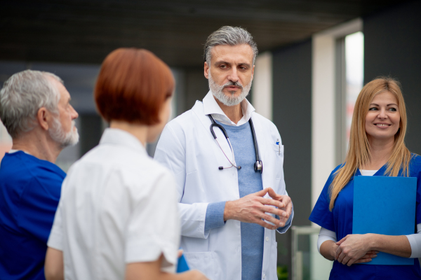 Team of doctors discussing unique medical case, walking across corridor. Colleagues, doctors team discussing patients diagnosis. in modern hospital, clinic.