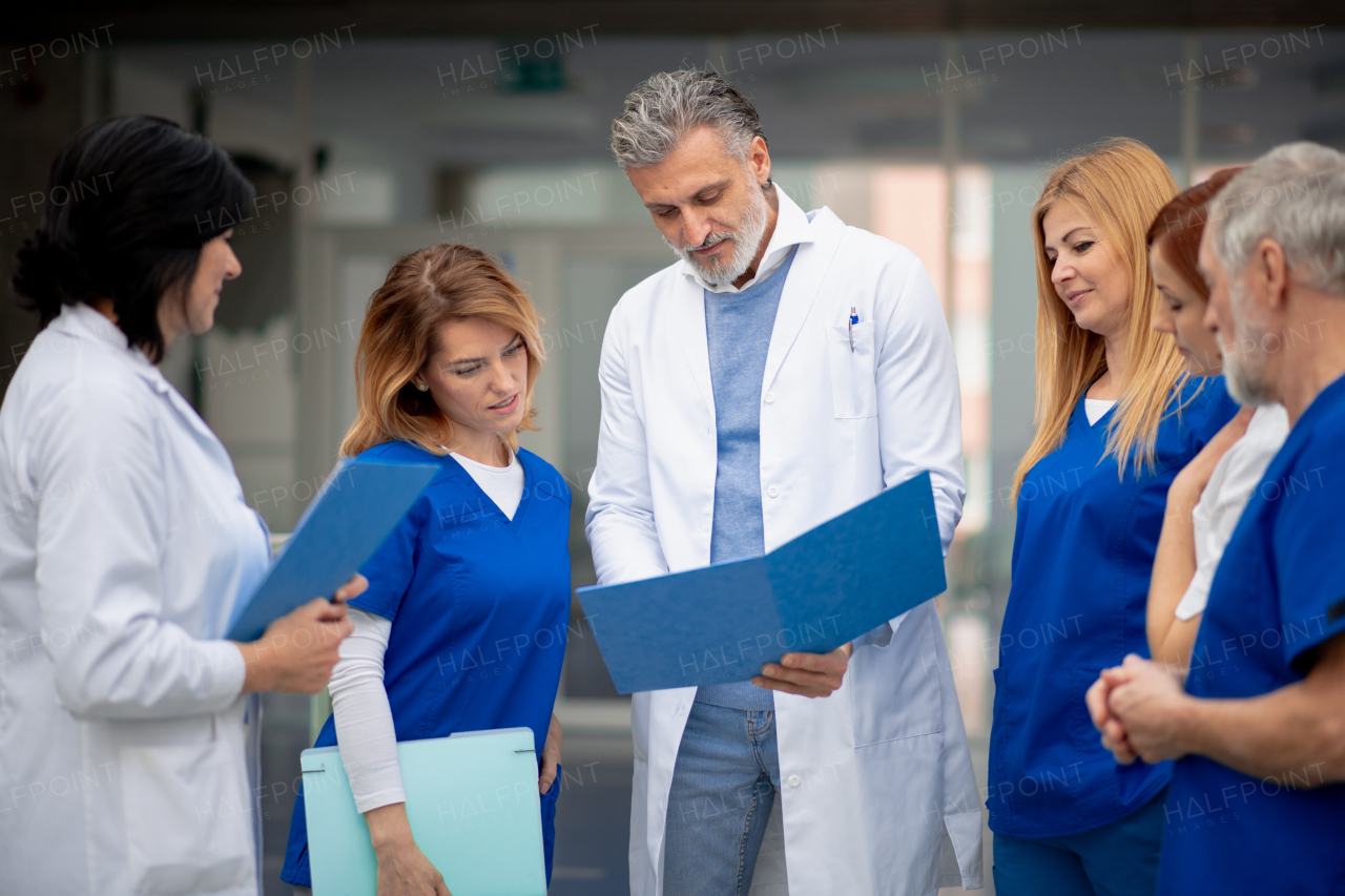 Team of doctors discussing unique medical case, walking across corridor. Colleagues, doctors team discussing patients diagnosis. in modern hospital, clinic.