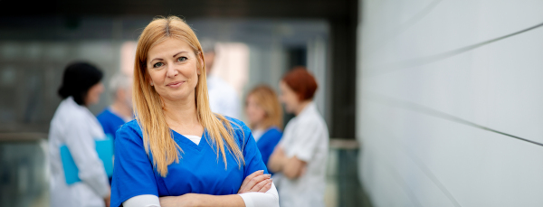 Portrait of beautiful female doctor standing in front of team of doctors. Colleagues, doctors team discussing patients diagnosis. in modern hospital, clinic. Banner with copy space. Woman in medical science.