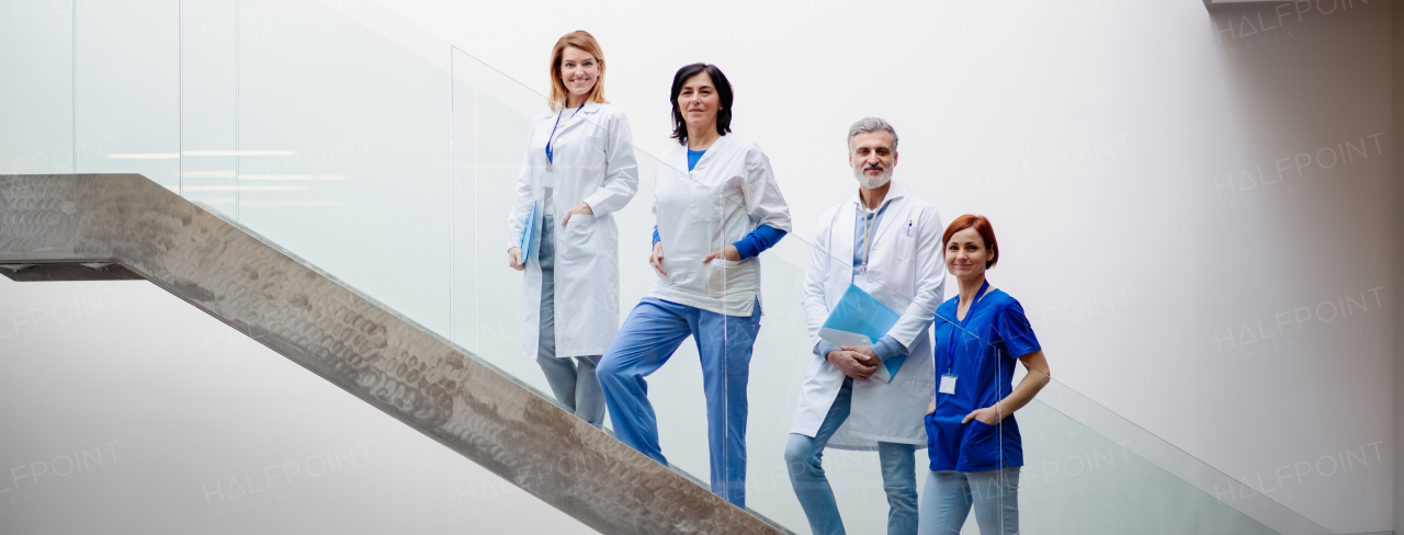 Portrait of team of doctors standing on modern stairs. Healthcare team with doctors, nurses, professionals in medical uniforms in hospital, modern clinic.