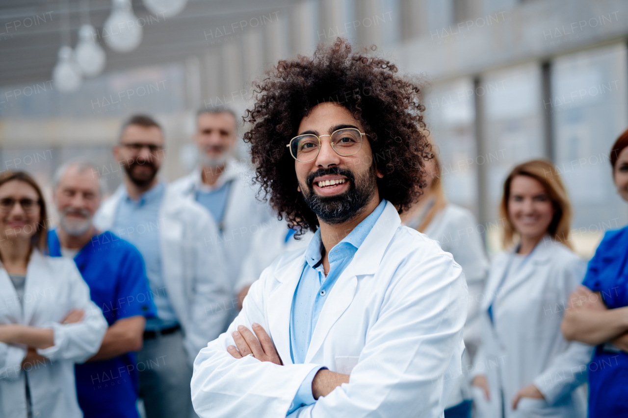 Portrait of ghandsome doctor standing in front of team of doctors. Healthcare team with doctors, nurses, professionals in medical uniforms in hospital, modern clinic.