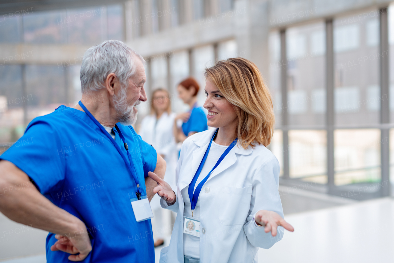 Young and older doctor talking during conference, discussing research findings. Medical networking. Medical experts attending an education event, seminar in board room.