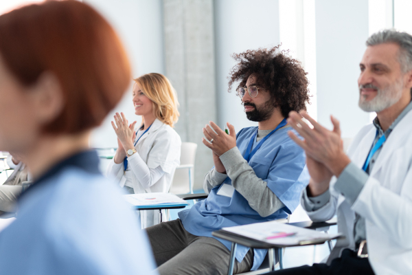 Group of doctors on conference, medical team sitting and clapping after speech. Medical experts attending an education event, seminar in board room.