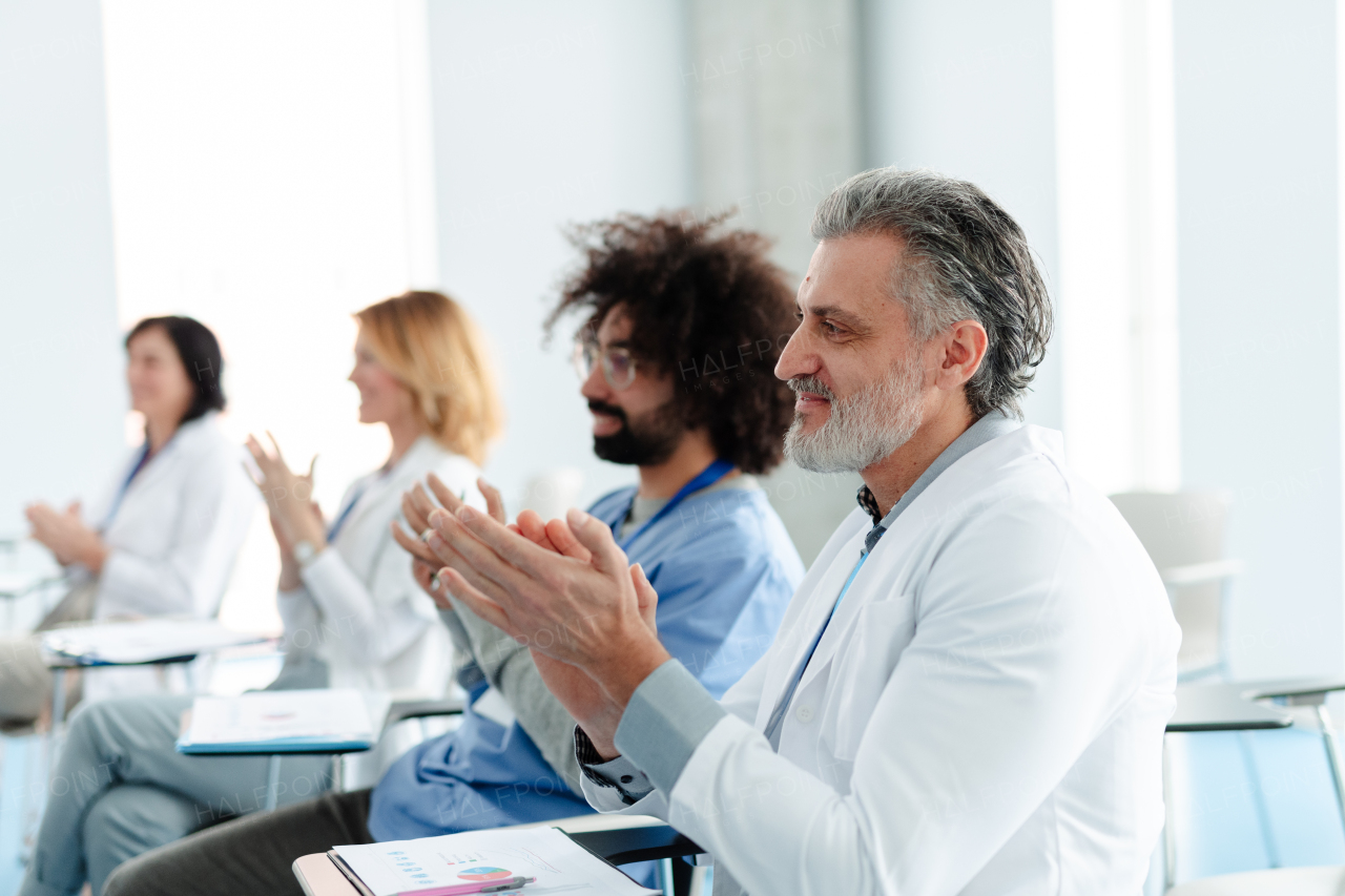 Group of doctors on conference, medical team sitting and clapping after speech. Medical experts attending an education event, seminar in board room.