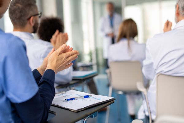 Group of doctors on conference, medical team sitting and clapping after speech. Medical experts attending an education event, seminar in board room.