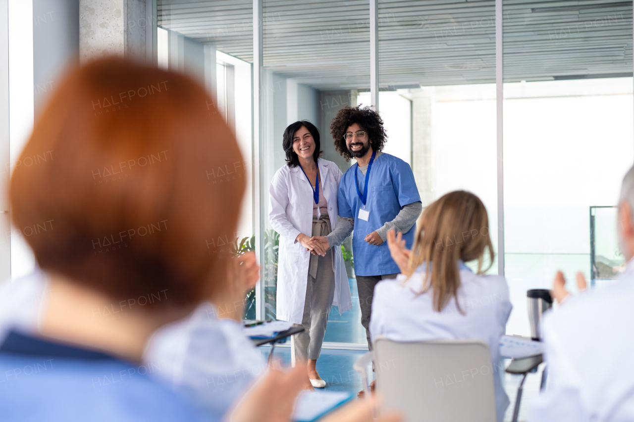 Female doctor as speaker at conference for group of healtcare workers, medical team sitting and listening presenter. Medical experts attending an education event, seminar in board room.