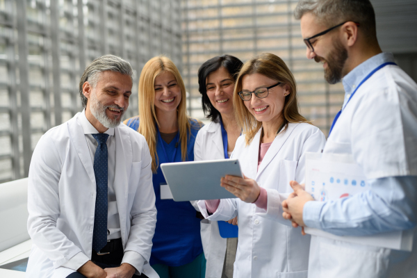 Group of doctors discussing test results, looking on tablet, medical team discussing patients diagnosis, searchign for right treatments.