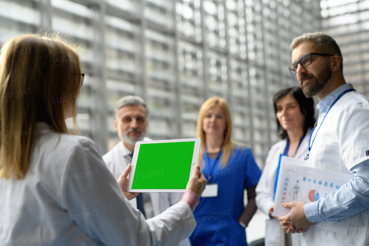 Group of doctors discussing test results, looking on tablet, medical team discussing patients diagnosis, searchign for right treatments. Display with mockup screen, placeholder.