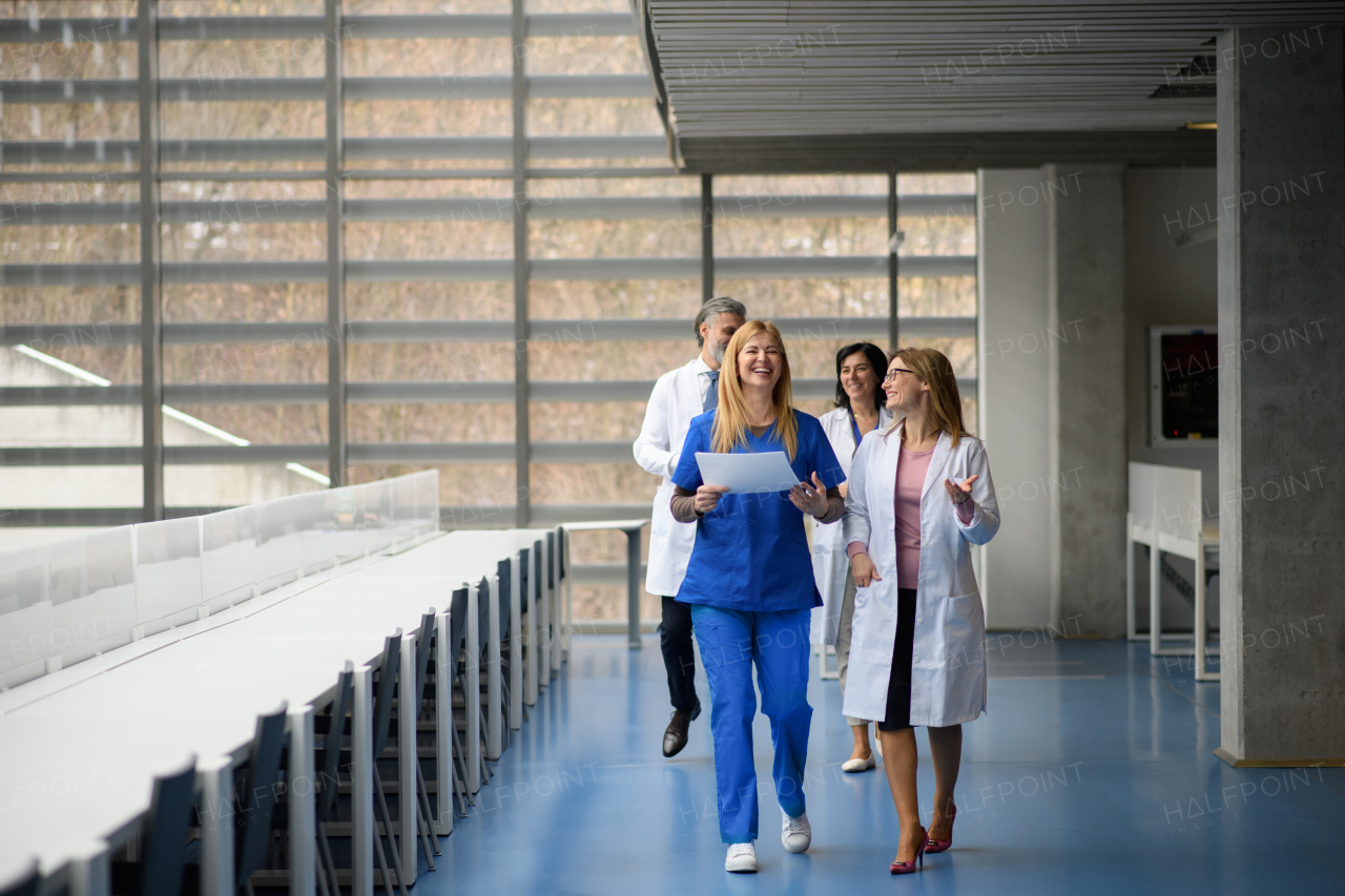 Two female doctors discussing test results, walking across corridor. Colleagues discussing patients diagnosis. Women in medicine science