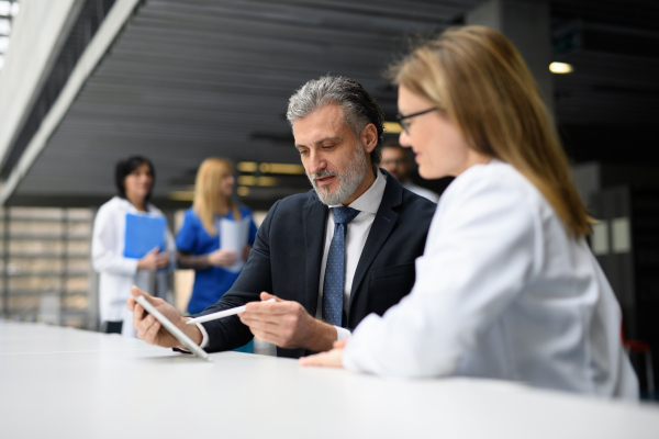 Doctors talking to pharmaceutical sales representative, shaking hands, presenting new pharmaceutical product. Hospital director, manager talking with female doctor.