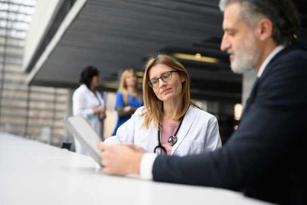 Doctors talking to pharmaceutical sales representative, shaking hands, presenting new pharmaceutical product. Hospital director, manager talking with female doctor.