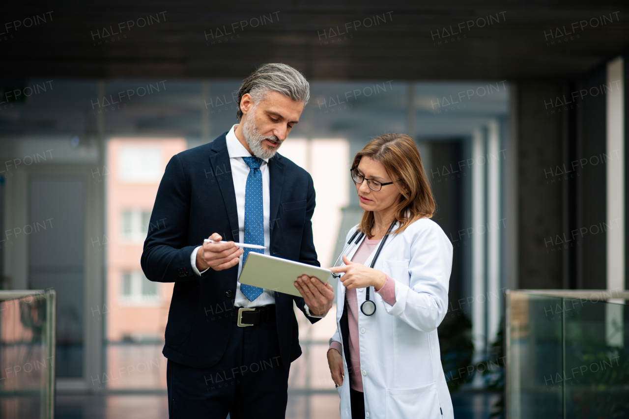 Doctors talking to pharmaceutical sales representative, presenting new pharmaceutical product. Hospital director, manager talking with female doctor. Side view with copyspace.