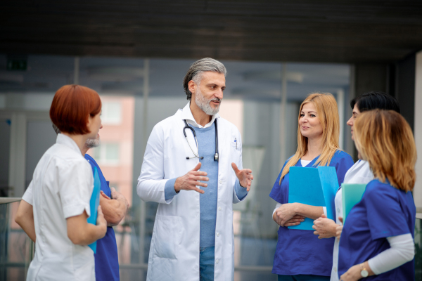 Team of doctors discussing unique medical case, walking across corridor. Colleagues, doctors team discussing patients diagnosis. in modern hospital, clinic.