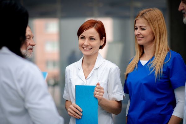 Team of doctors discussing unique surgery success, walking across corridor. Colleagues, doctors team discussing patients diagnosis. in modern hospital, clinic.