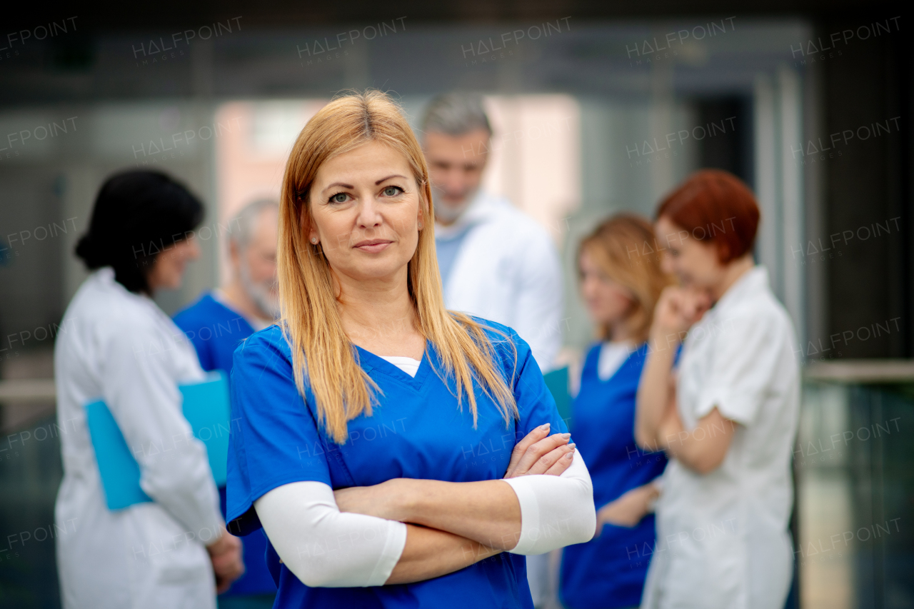 Portrait of beautiful female doctor standing in front of team of doctors. Colleagues, doctors team discussing patients diagnosis. in modern hospital, clinic.