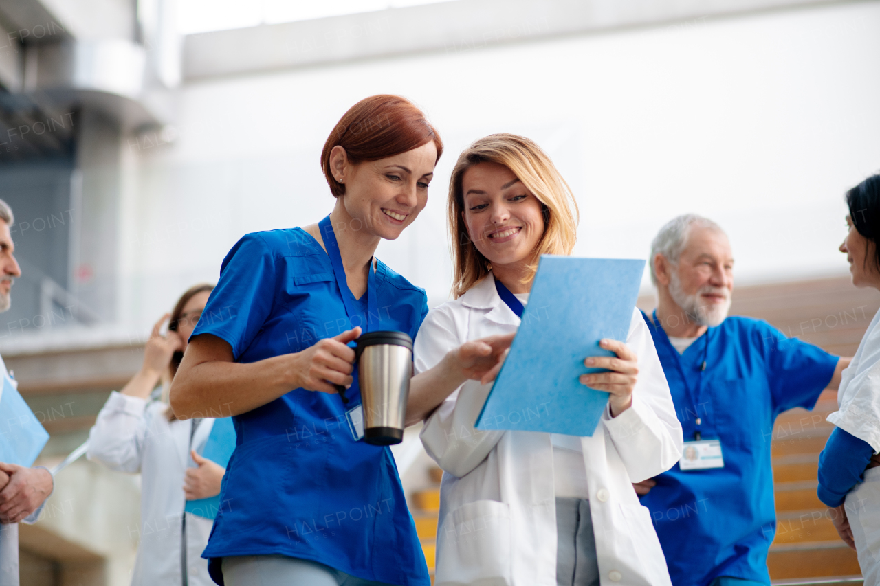 Team of doctors discussing unique surgery success, walking across corridor. Colleagues, doctors team discussing patients diagnosis. in modern hospital, clinic.