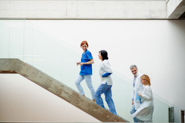 Portrait of team of doctors standing on modern stairs. Healthcare team with doctors, nurses, professionals in medical uniforms in hospital, modern clinic.